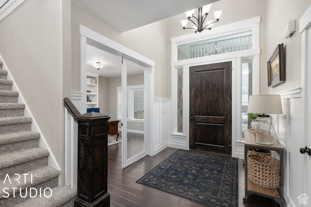 Foyer entrance with an inviting chandelier and dark hardwood / wood-style floors