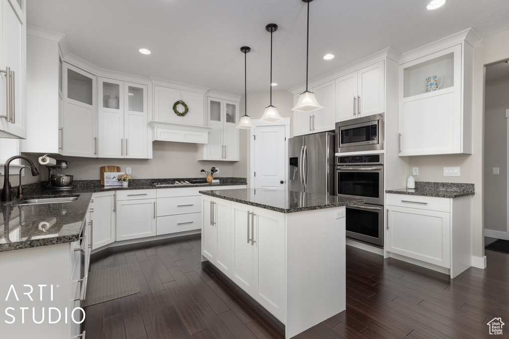 Kitchen with a center island, dark wood-type flooring, sink, pendant lighting, and appliances with stainless steel finishes