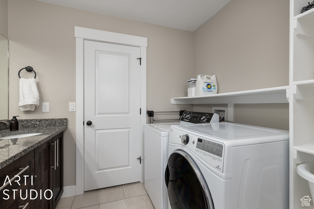 Laundry room with light tile flooring, sink, hookup for a washing machine, and washing machine and clothes dryer