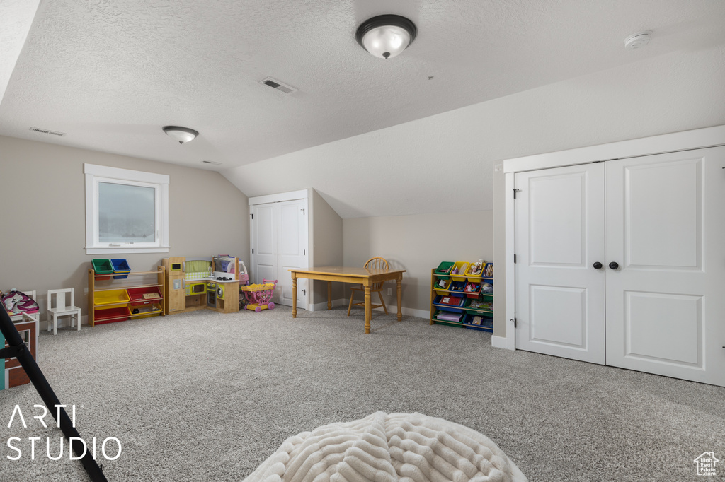 Game room with light colored carpet, a textured ceiling, and vaulted ceiling