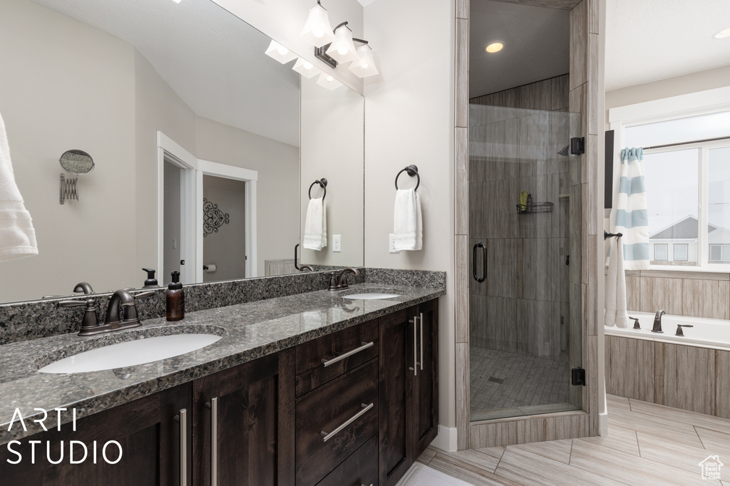 Bathroom with dual bowl vanity, shower with separate bathtub, and tile flooring