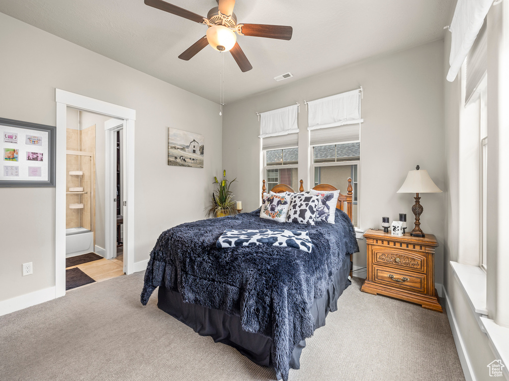 Bedroom with ensuite bath, ceiling fan, and light colored carpet