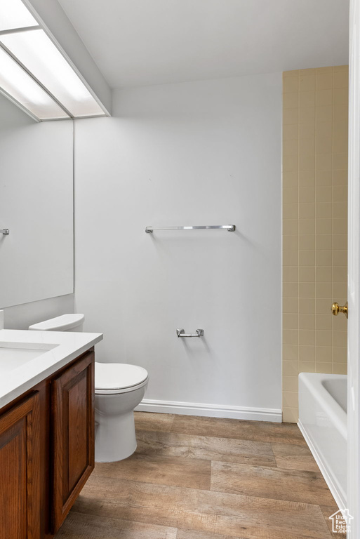 Full bathroom with vanity, toilet, hardwood / wood-style floors, and shower / washtub combination