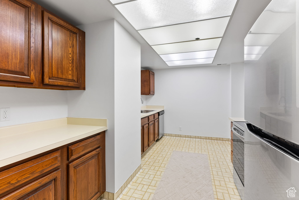 Kitchen featuring sink, light tile floors, and stainless steel dishwasher