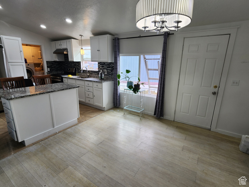Kitchen featuring white cabinetry, a chandelier, range, and washer / clothes dryer