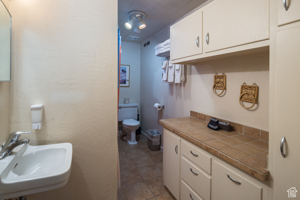 Bathroom with toilet, tile flooring, and sink