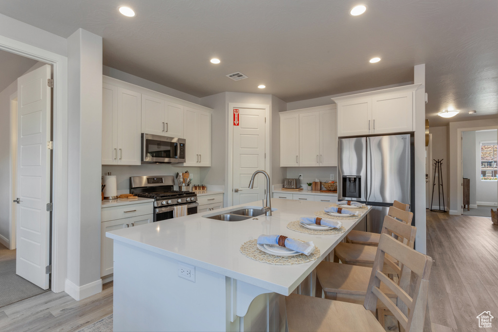 Kitchen featuring light wood-type flooring, stainless steel appliances, a kitchen breakfast bar, and sink