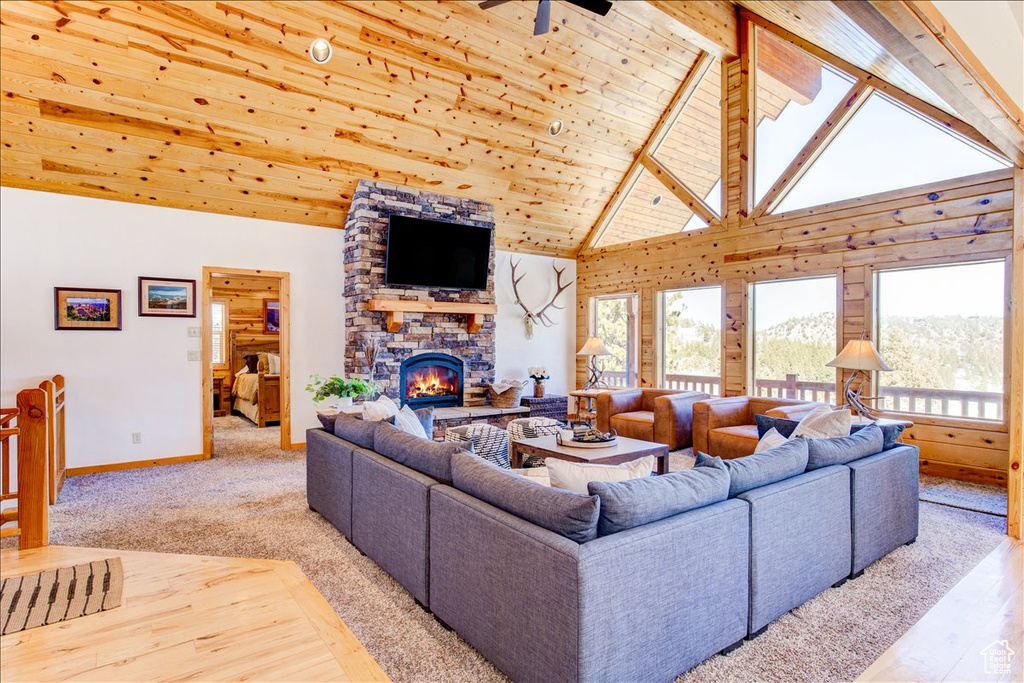 Carpeted living room with a fireplace, ceiling fan, wooden ceiling, high vaulted ceiling, and beam ceiling