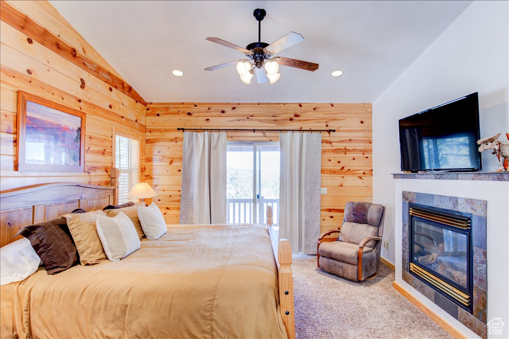 Carpeted bedroom with vaulted ceiling, access to exterior, wooden walls, and ceiling fan