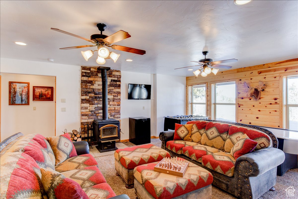 Living room with brick wall, ceiling fan, light colored carpet, and a wood stove
