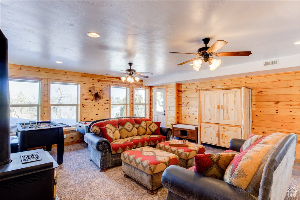 Living room featuring wood walls, ceiling fan, and light carpet