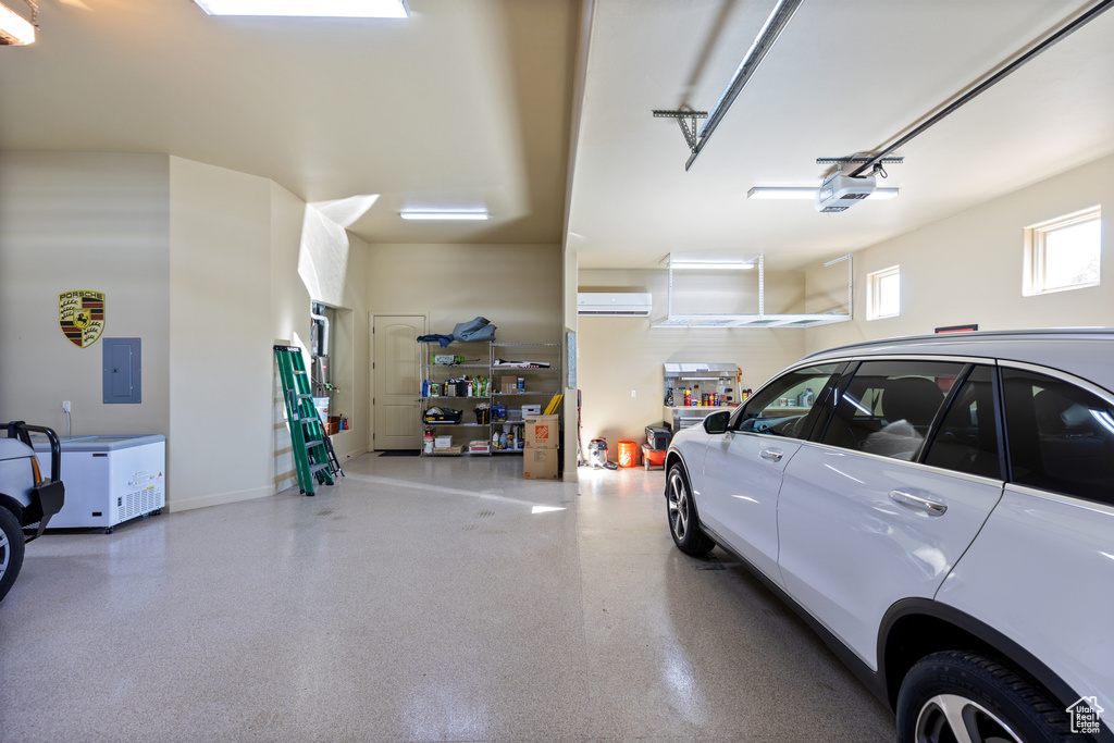 Garage featuring a wall mounted AC and a garage door opener