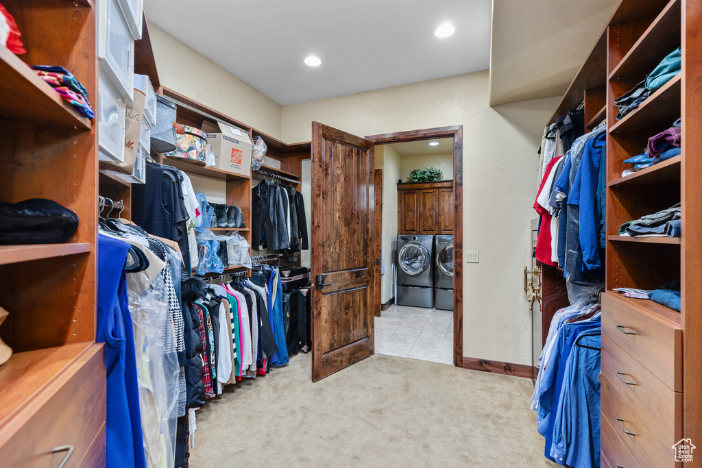 Walk in closet featuring washing machine and dryer and light carpet