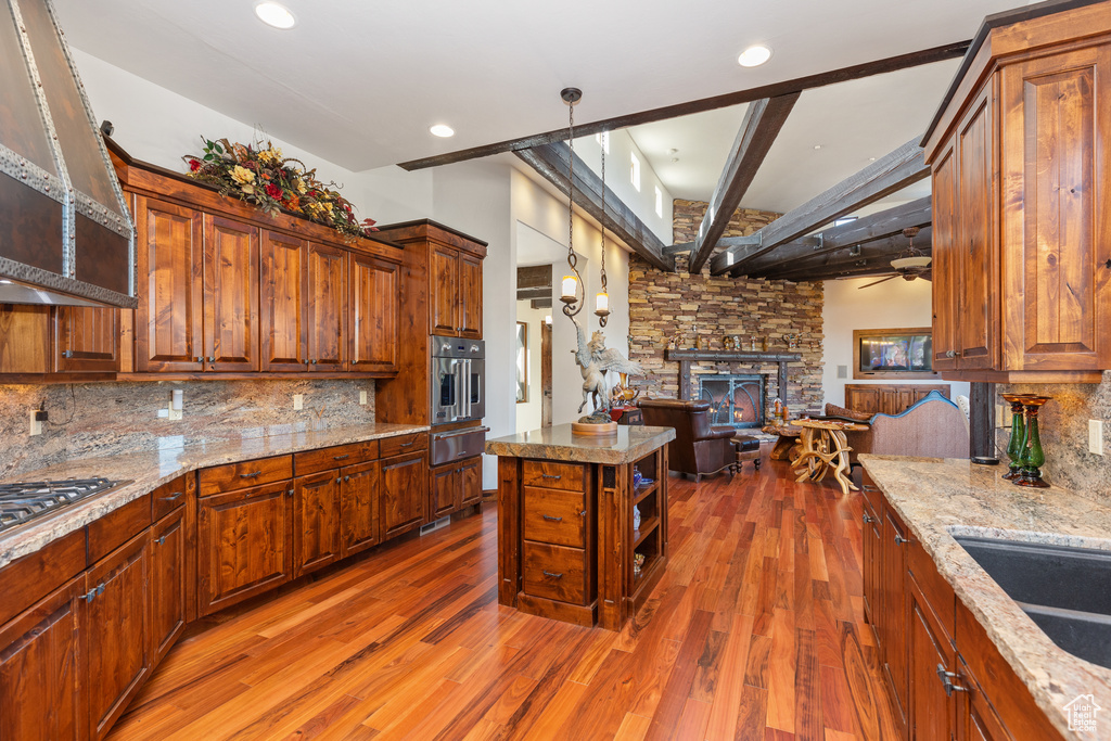 Kitchen featuring dark wood-type flooring, beamed ceiling, a fireplace, tasteful backsplash, and ceiling fan