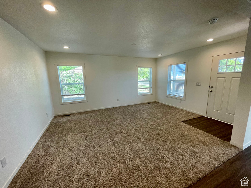 Empty room featuring a healthy amount of sunlight and dark carpet