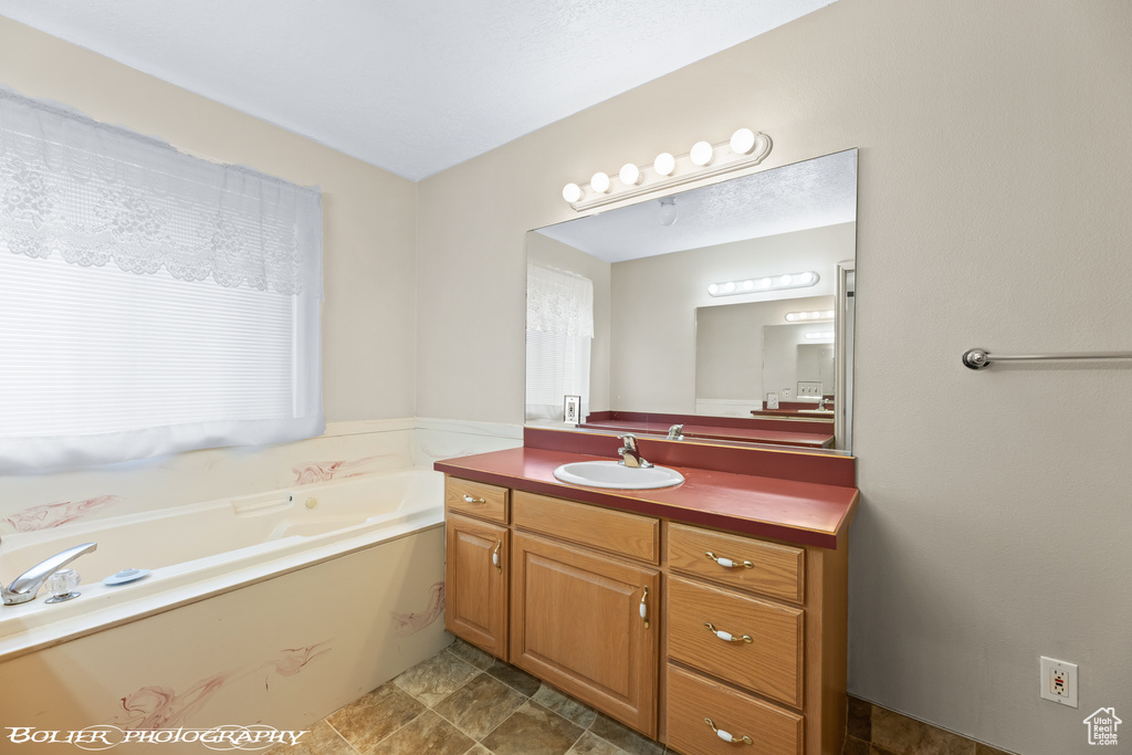 Bathroom featuring tile floors, vanity, and a bath