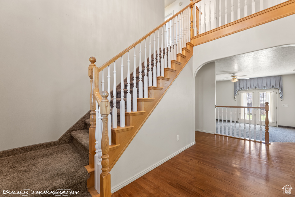 Stairway featuring hardwood / wood-style floors, ceiling fan, and french doors