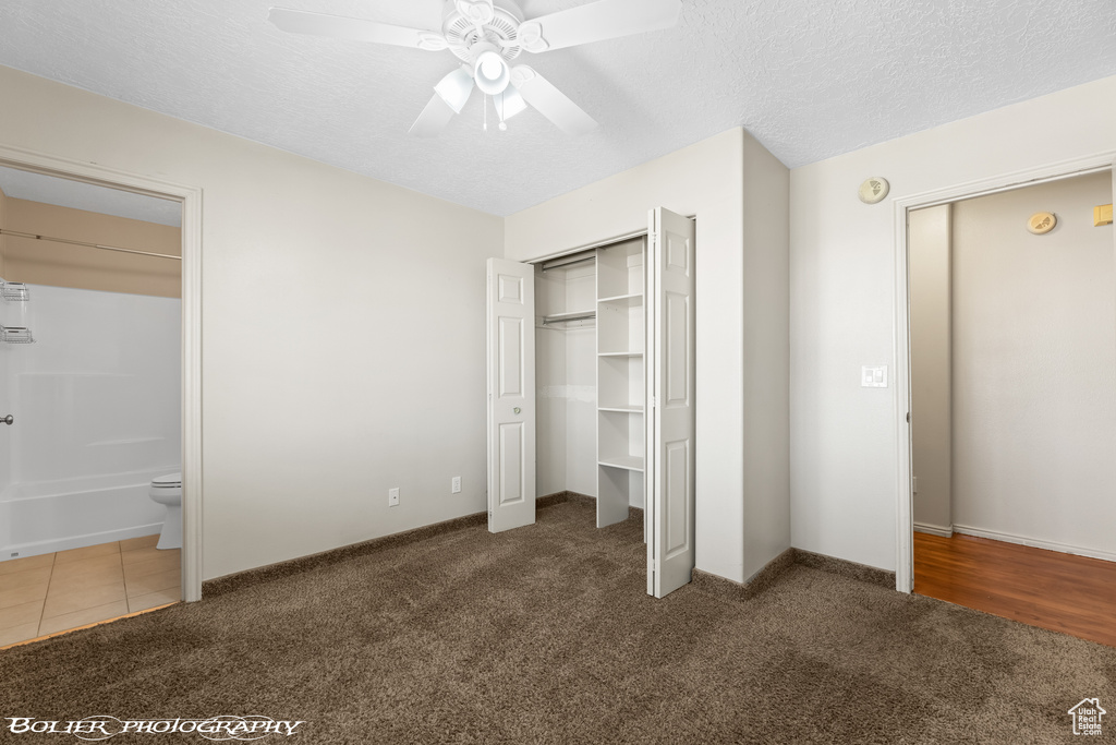 Unfurnished bedroom with dark carpet, a closet, ceiling fan, and a textured ceiling