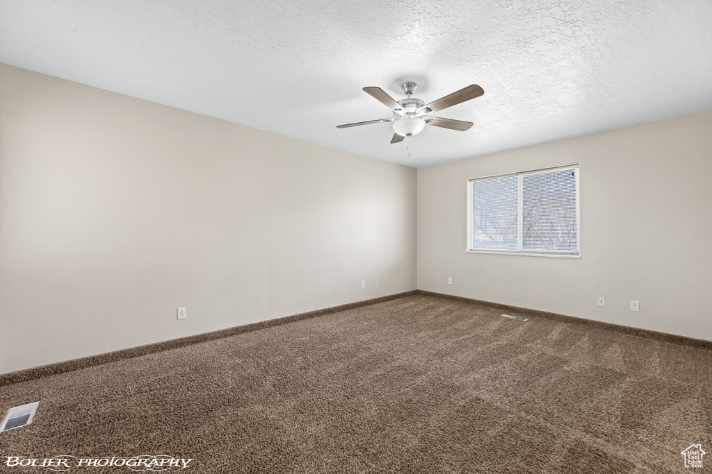 Spare room featuring ceiling fan, a textured ceiling, and carpet flooring