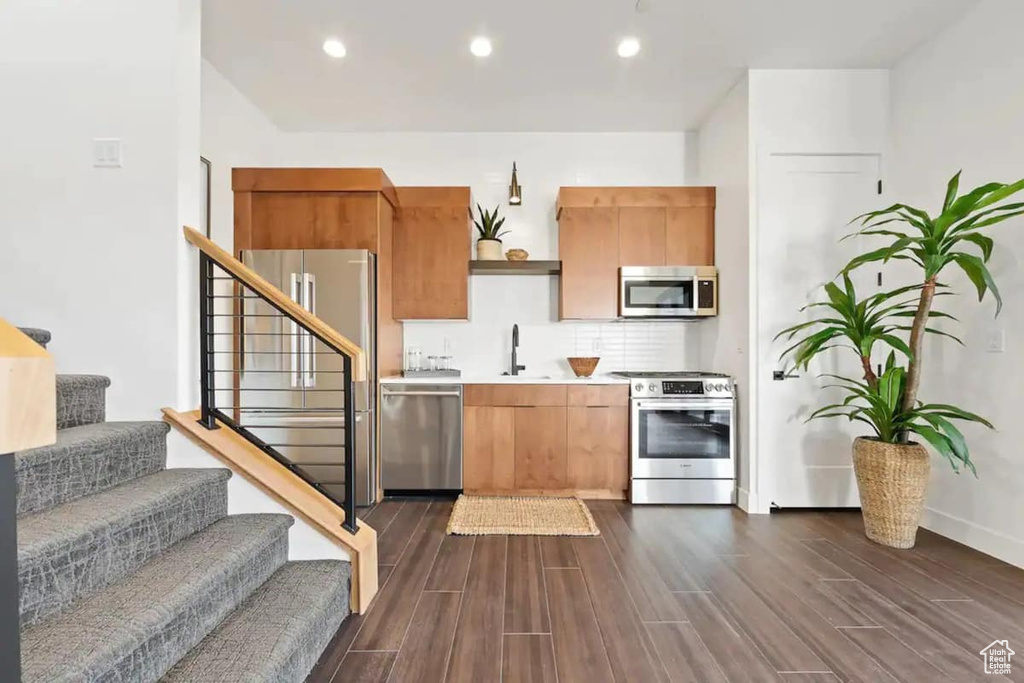 Kitchen featuring tasteful backsplash, dark hardwood / wood-style floors, appliances with stainless steel finishes, and sink