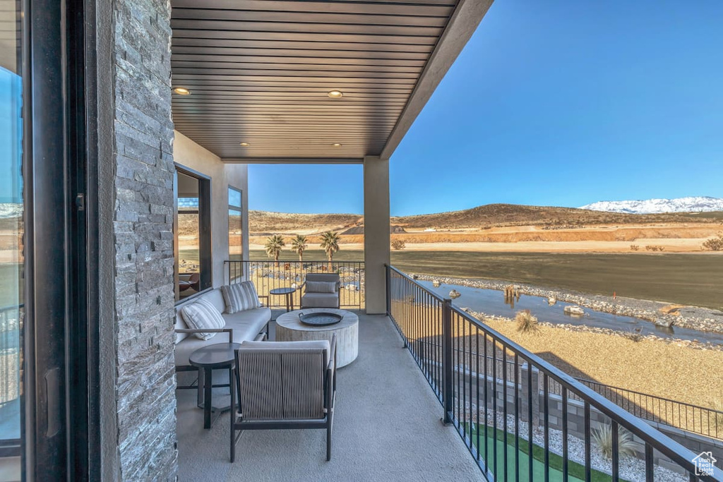Balcony featuring a water and mountain view and an outdoor fire pit