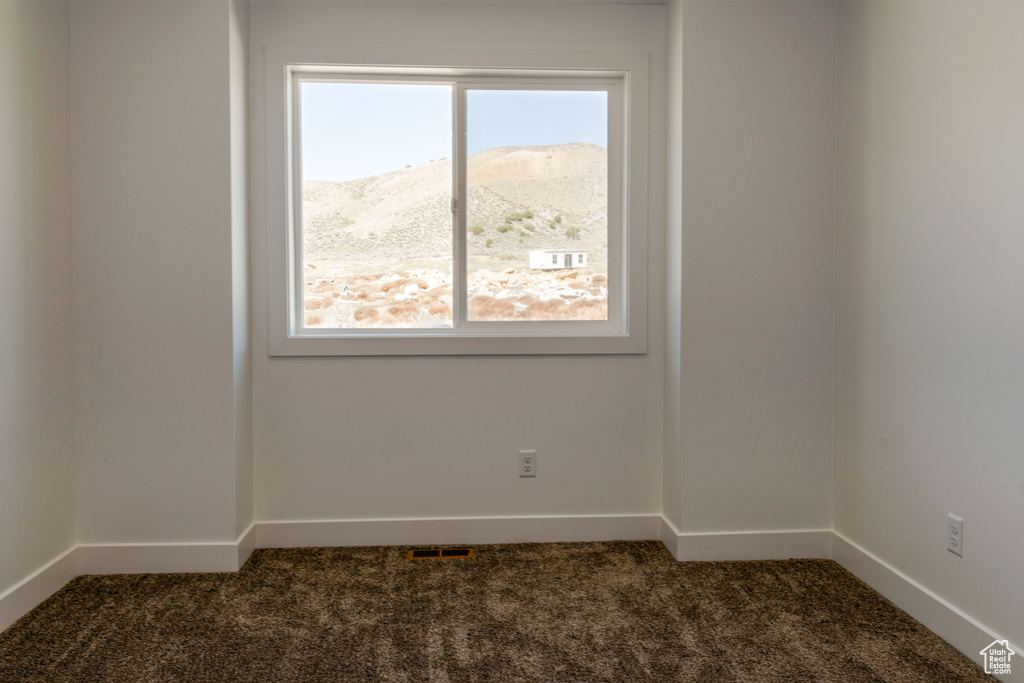 Spare room with a mountain view and dark colored carpet