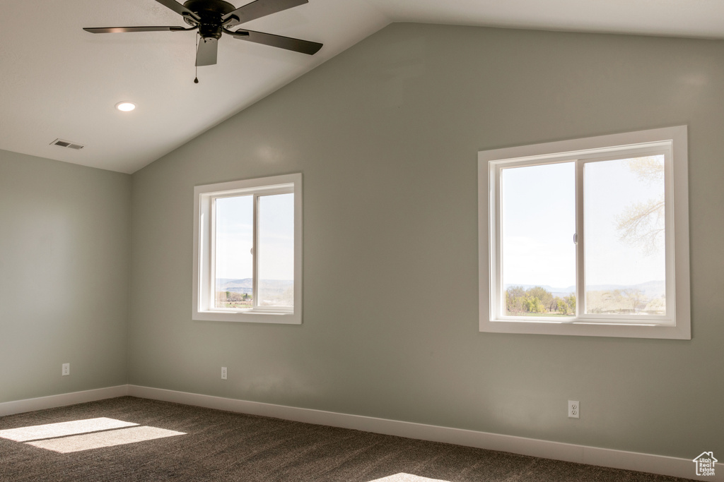 Carpeted empty room with a wealth of natural light, ceiling fan, and vaulted ceiling