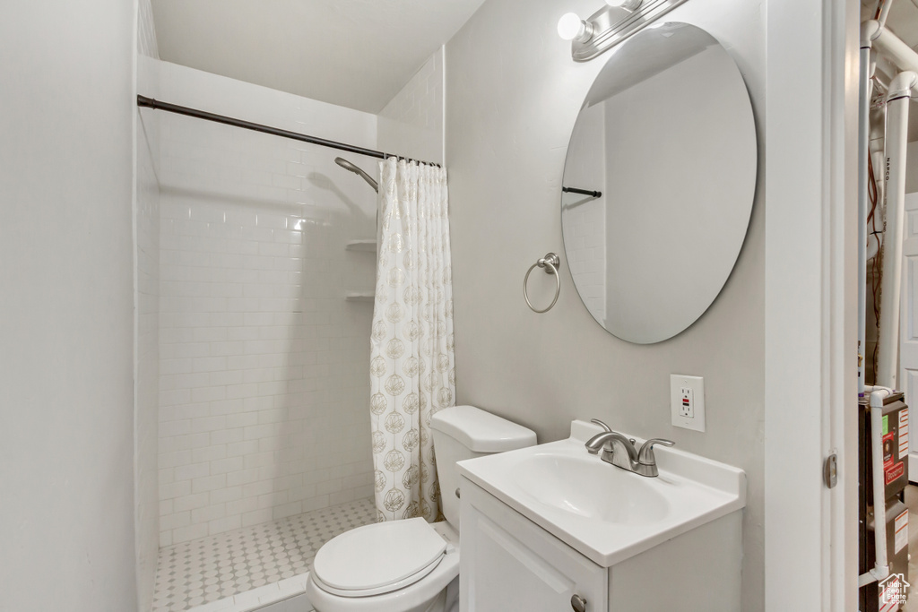 Bathroom featuring vanity, toilet, and curtained shower