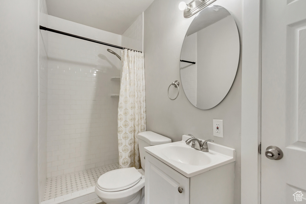 Bathroom featuring large vanity, a shower with shower curtain, and toilet