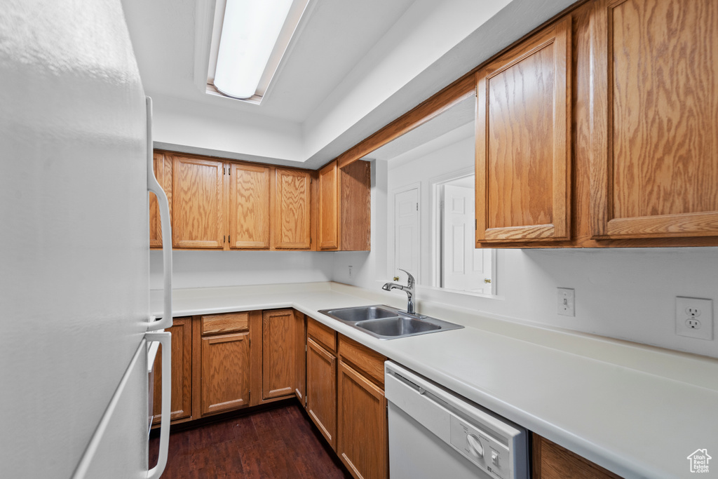 Kitchen with white appliances, dark hardwood / wood-style flooring, and sink