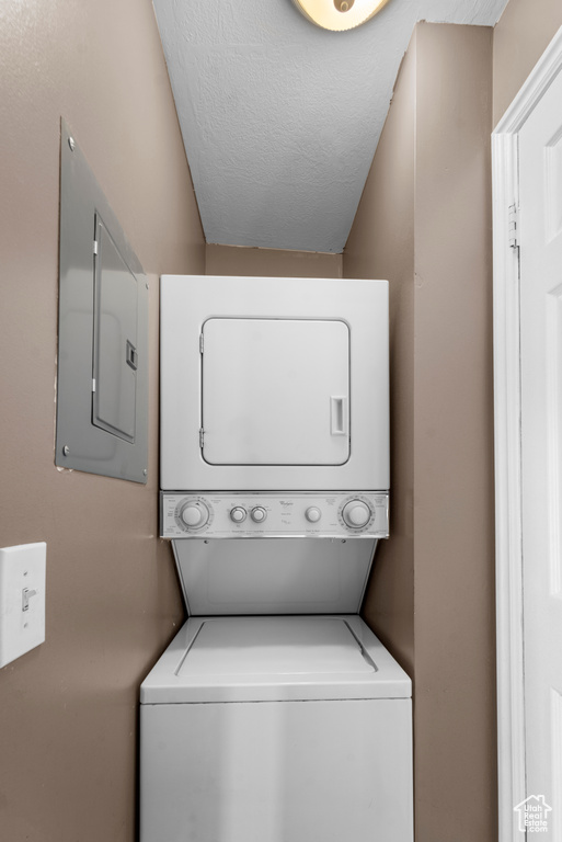 Laundry area featuring stacked washer and clothes dryer and a textured ceiling
