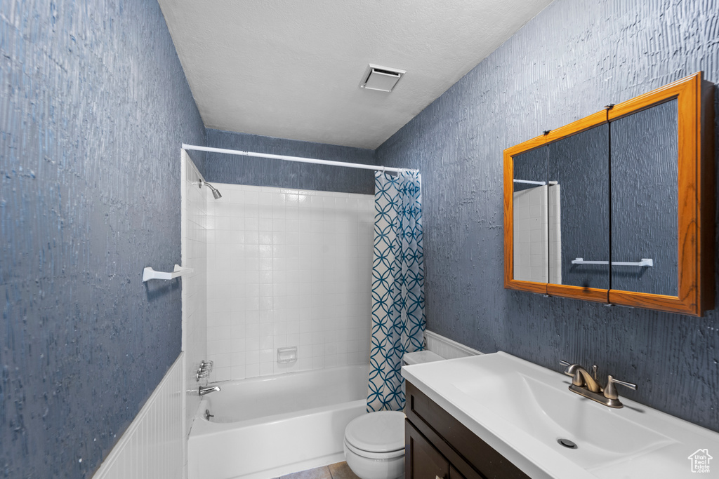 Full bathroom featuring vanity with extensive cabinet space, shower / tub combo, a textured ceiling, and toilet