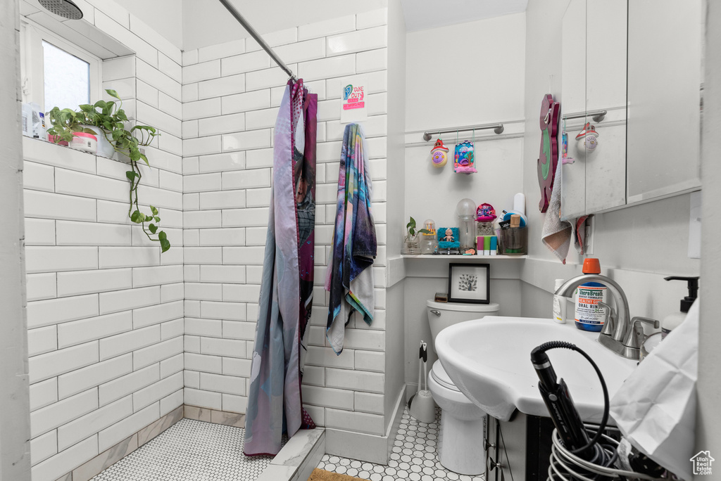 Bathroom with sink, tile flooring, a shower with shower curtain, and toilet