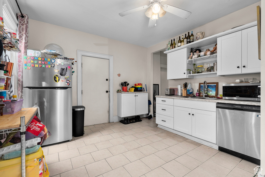 Kitchen featuring white cabinets, appliances with stainless steel finishes, light tile floors, and ceiling fan