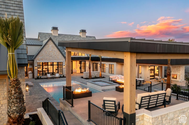 Back house at dusk featuring an outdoor living space with a fire pit and a patio area