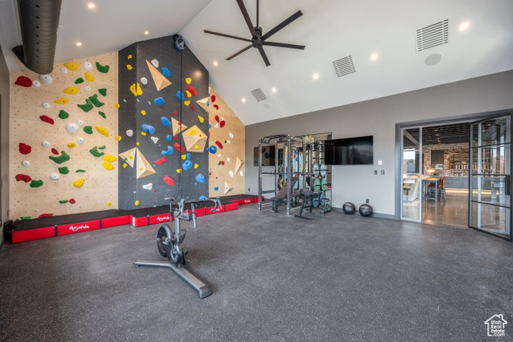 Exercise area with ceiling fan and high vaulted ceiling