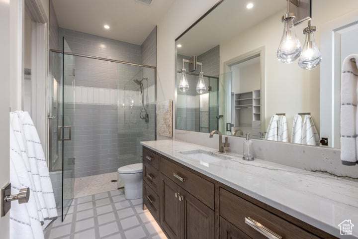 Bathroom featuring walk in shower, vanity, tile flooring, and toilet