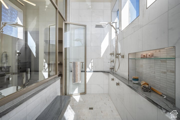Bathroom with a healthy amount of sunlight, tile walls, and a shower with shower door