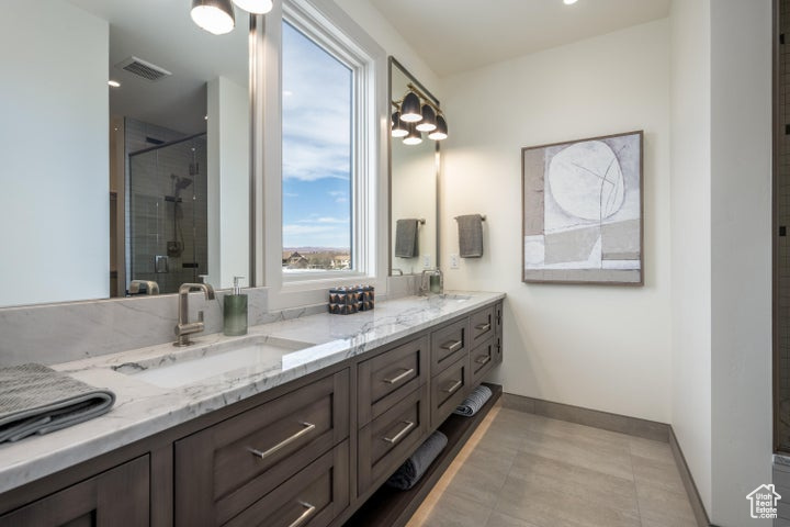 Bathroom with an enclosed shower, oversized vanity, tile flooring, and dual sinks