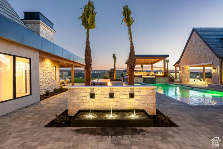 Pool at dusk featuring a patio and an outdoor kitchen