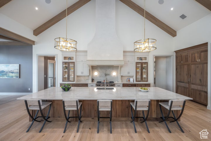 Kitchen featuring white cabinetry, a breakfast bar area, hanging light fixtures, and a large island