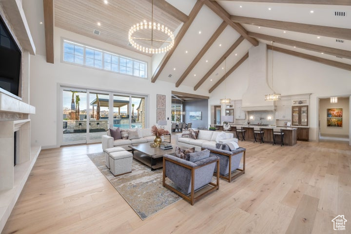 Living room with a towering ceiling, a notable chandelier, and light hardwood / wood-style floors
