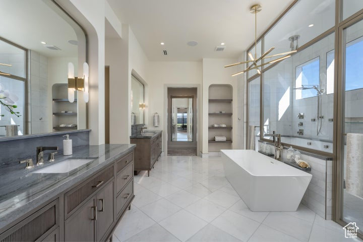 Bathroom with a notable chandelier, oversized vanity, tile floors, and plus walk in shower