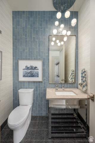 Bathroom with tile floors, vanity, toilet, and tile walls