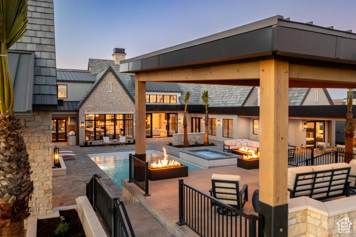 Back house at dusk featuring an outdoor living space with a fire pit and a patio
