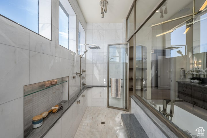 Bathroom featuring combined bath / shower with glass door, tile walls, and vanity