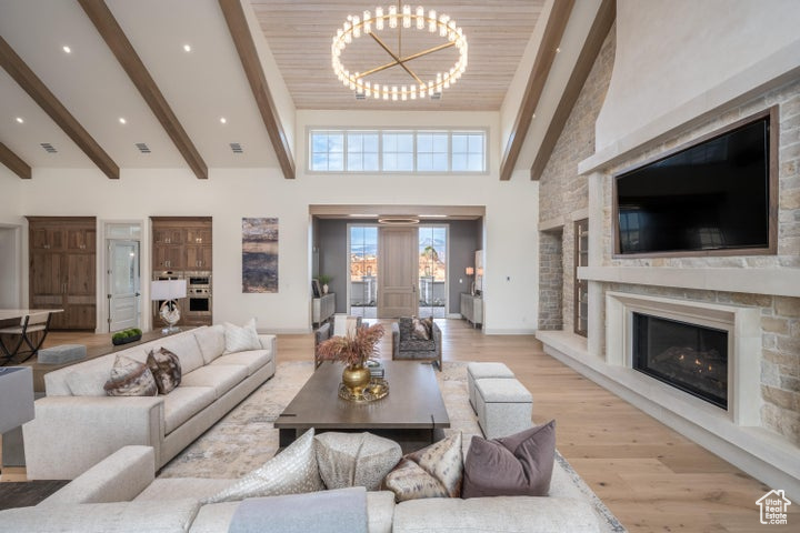 Living room featuring an inviting chandelier, light hardwood / wood-style flooring, a fireplace, and high vaulted ceiling
