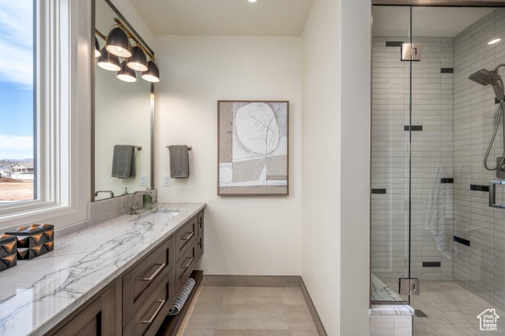 Bathroom featuring vanity with extensive cabinet space, an enclosed shower, and tile floors