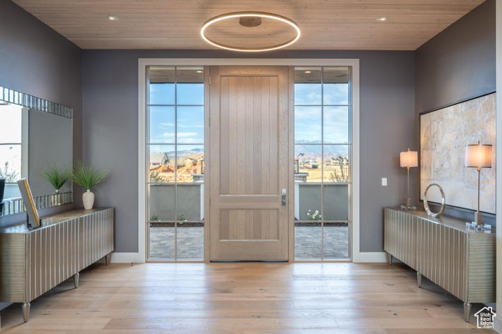 Doorway to outside with a wealth of natural light, wood ceiling, and light hardwood / wood-style floors