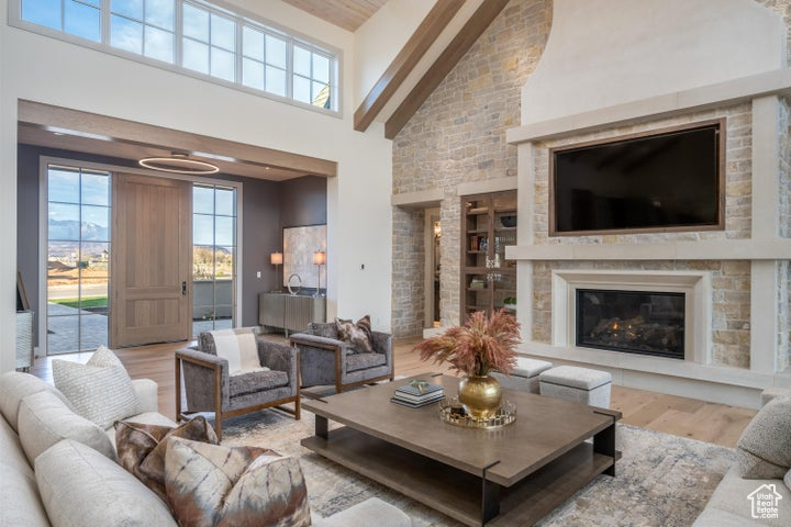 Living room with high vaulted ceiling, light hardwood / wood-style flooring, beamed ceiling, and a large fireplace